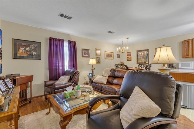 living area with light wood-style floors, a notable chandelier, and visible vents