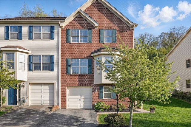 view of property with an attached garage, a front yard, driveway, and brick siding