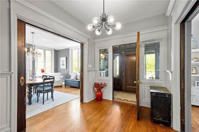 doorway with crown molding, a chandelier, and hardwood / wood-style floors