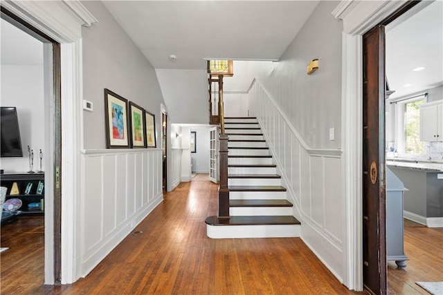 stairs with wainscoting, hardwood / wood-style flooring, and a decorative wall