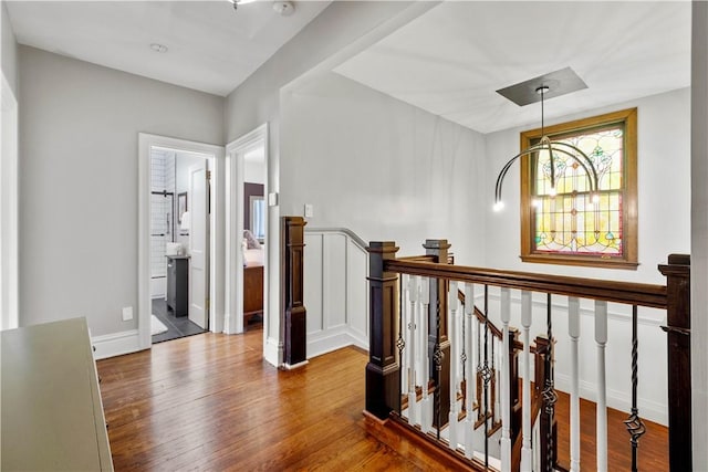 hall with baseboards, wood finished floors, and an upstairs landing
