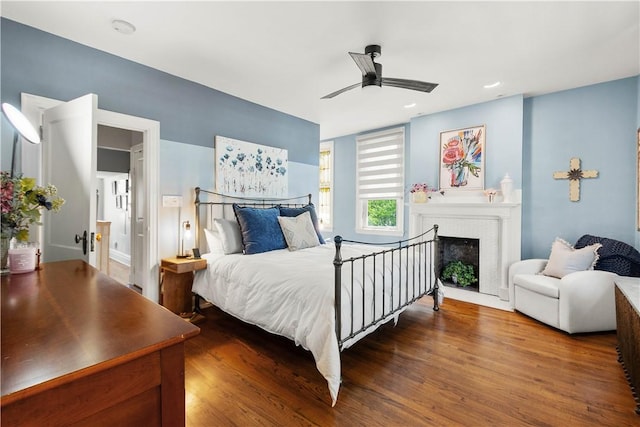 bedroom featuring recessed lighting, a ceiling fan, wood finished floors, and a fireplace