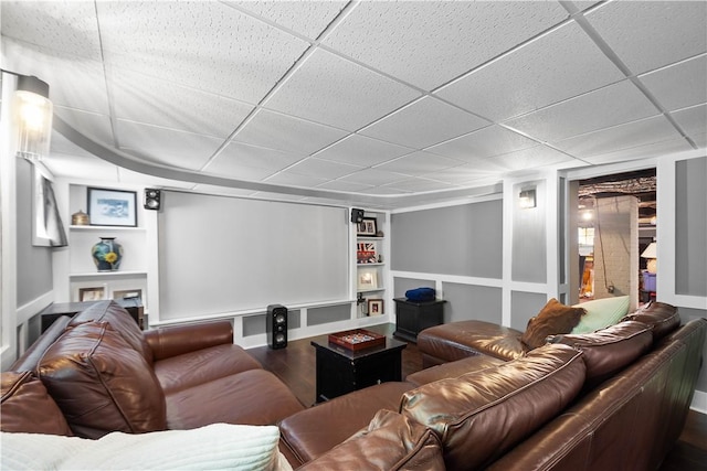 home theater room with baseboards, a paneled ceiling, dark wood-style flooring, and built in shelves