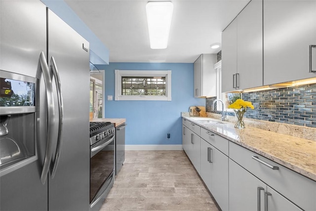 kitchen with baseboards, a sink, appliances with stainless steel finishes, and tasteful backsplash
