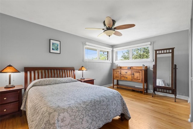 bedroom with light wood-style floors, baseboards, multiple windows, and ceiling fan