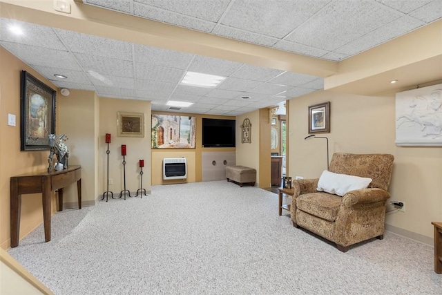living area with heating unit, baseboards, a drop ceiling, and carpet flooring