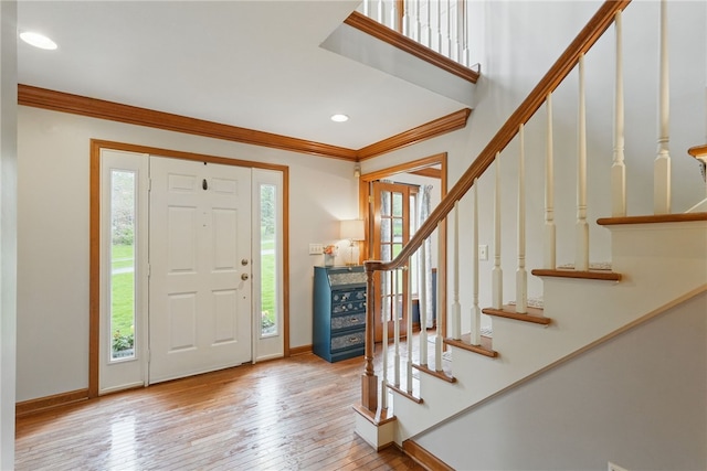 entryway with crown molding, baseboards, and stairway