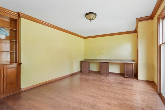 unfurnished office with crown molding, light wood-style floors, and baseboards