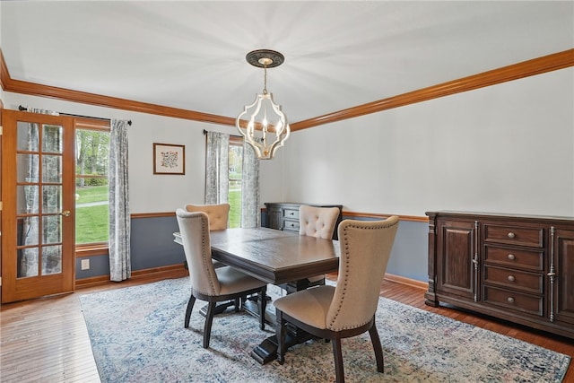 dining area with crown molding, baseboards, wood finished floors, and a notable chandelier