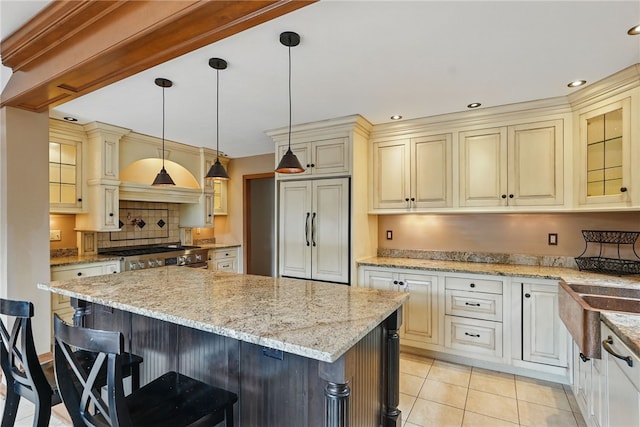 kitchen with a kitchen island, a breakfast bar, cream cabinetry, and stainless steel gas stove