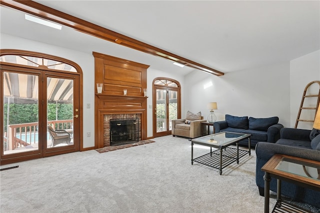 living area featuring a fireplace with flush hearth, plenty of natural light, light carpet, and beam ceiling
