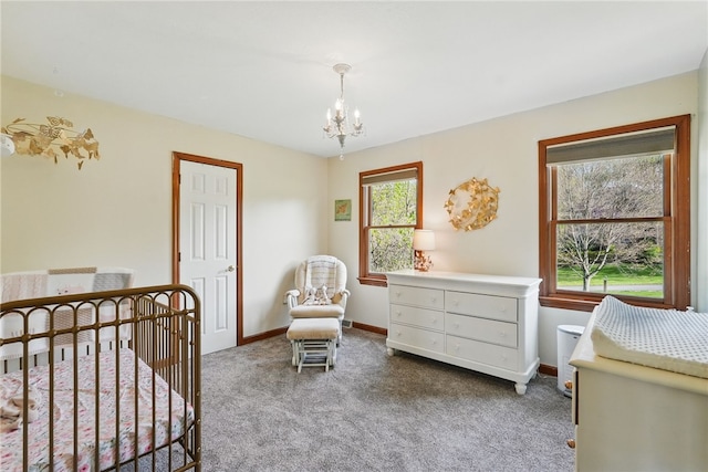 carpeted bedroom featuring a nursery area, baseboards, and a notable chandelier