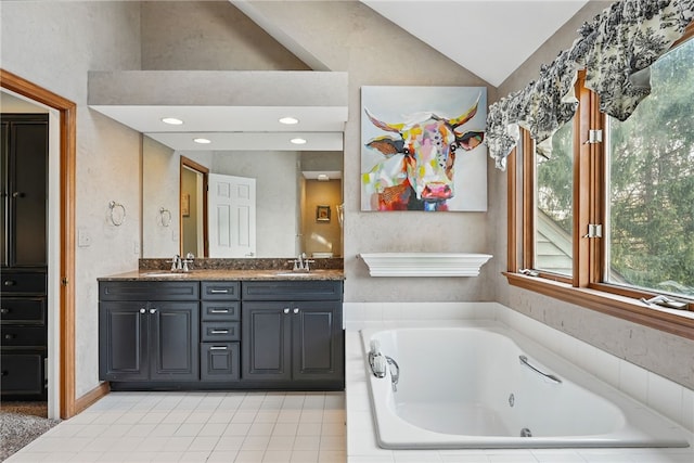 full bath with double vanity, vaulted ceiling, a tub with jets, and a sink