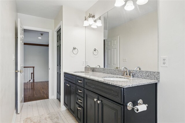 bathroom featuring double vanity, a sink, baseboards, and tile patterned floors