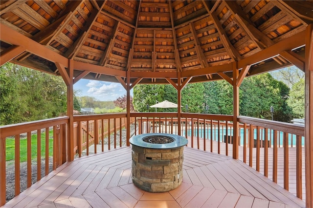wooden deck featuring a gazebo, a fire pit, and an outdoor pool