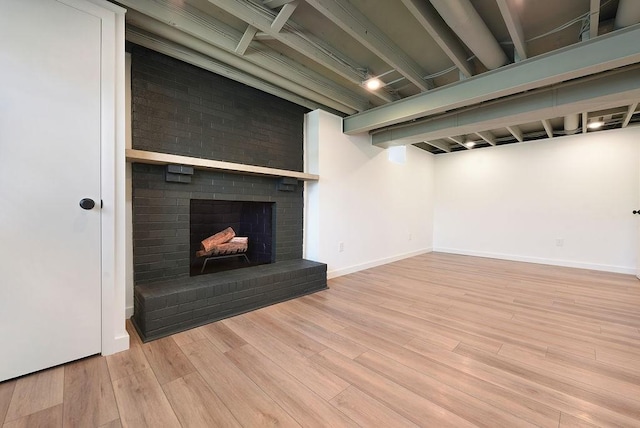 unfurnished living room with baseboards, wood finished floors, and a fireplace
