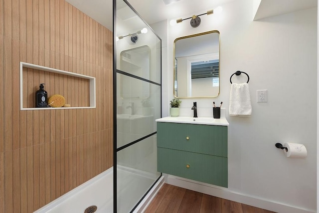 bathroom featuring vanity, wood finished floors, and a tile shower