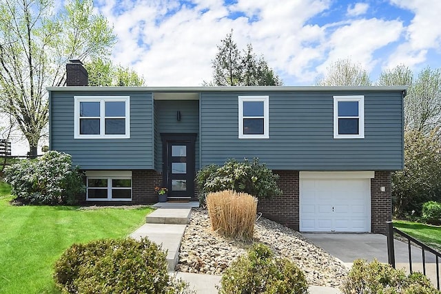 bi-level home featuring an attached garage, a front lawn, brick siding, a chimney, and concrete driveway