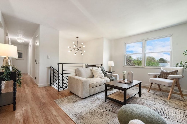 living area featuring light wood-style floors, baseboards, and a notable chandelier