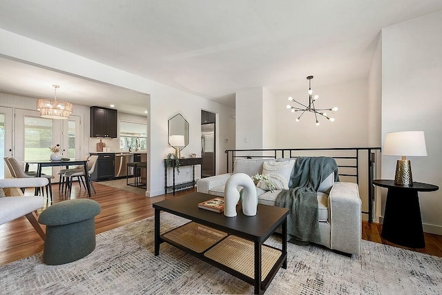 living room with baseboards, a notable chandelier, and light wood-style floors
