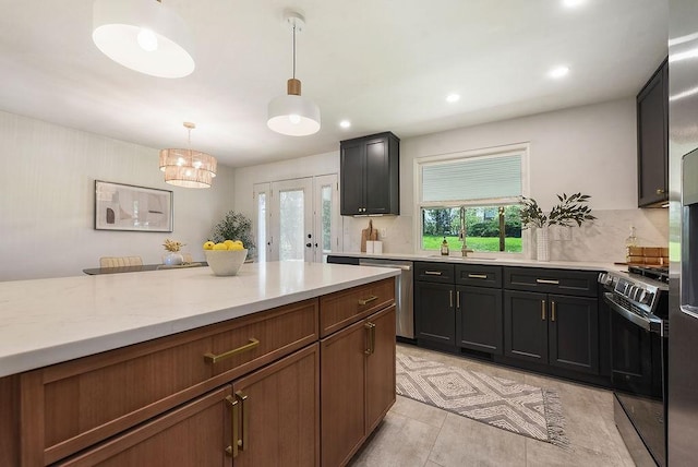 kitchen featuring hanging light fixtures, light stone counters, a sink, stainless steel appliances, and recessed lighting