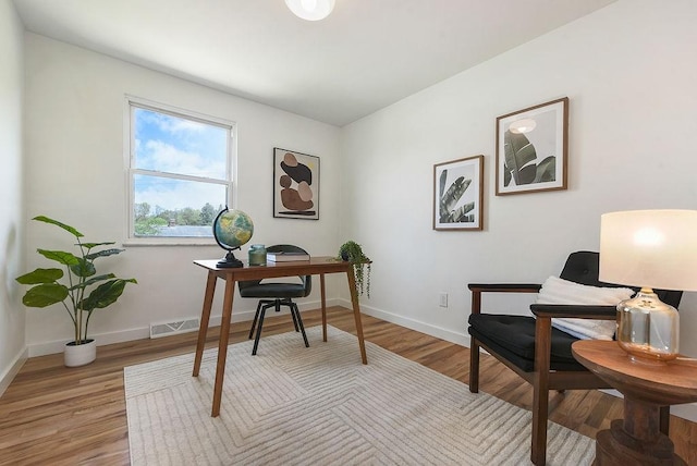 office with baseboards, light wood finished floors, and visible vents