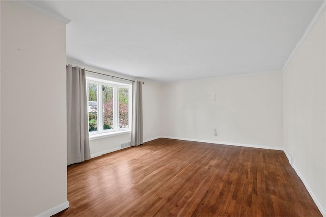 spare room featuring crown molding, baseboards, visible vents, and wood finished floors