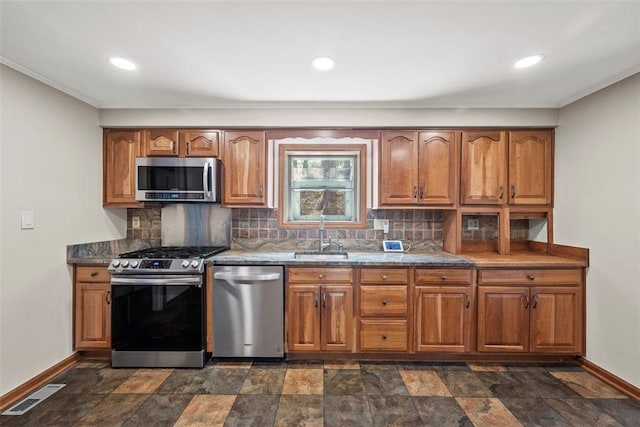 kitchen featuring stainless steel appliances, baseboards, visible vents, and a sink