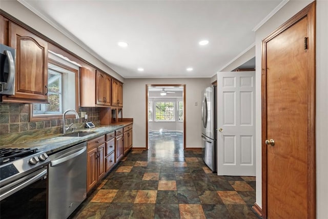 kitchen featuring a sink, stone finish floor, stainless steel appliances, baseboards, and decorative backsplash