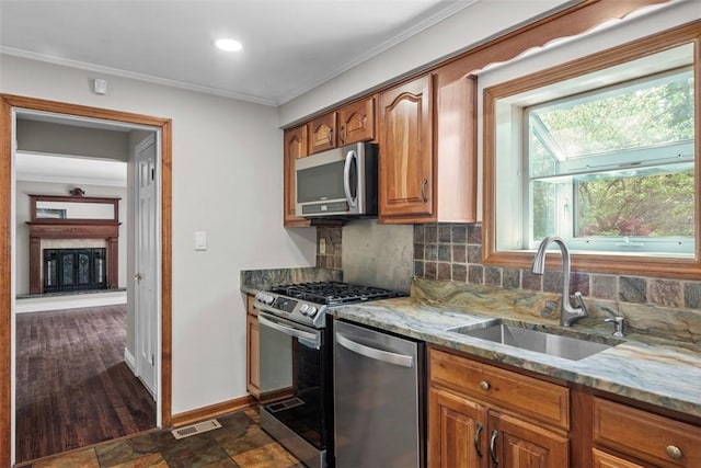 kitchen featuring light stone countertops, appliances with stainless steel finishes, a sink, decorative backsplash, and visible vents