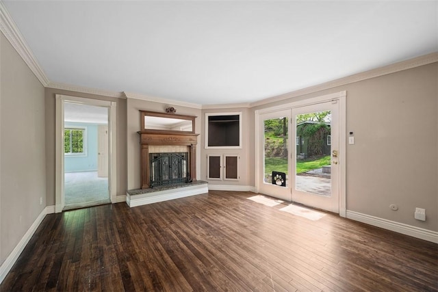 unfurnished living room with baseboards, a fireplace with raised hearth, crown molding, and wood finished floors