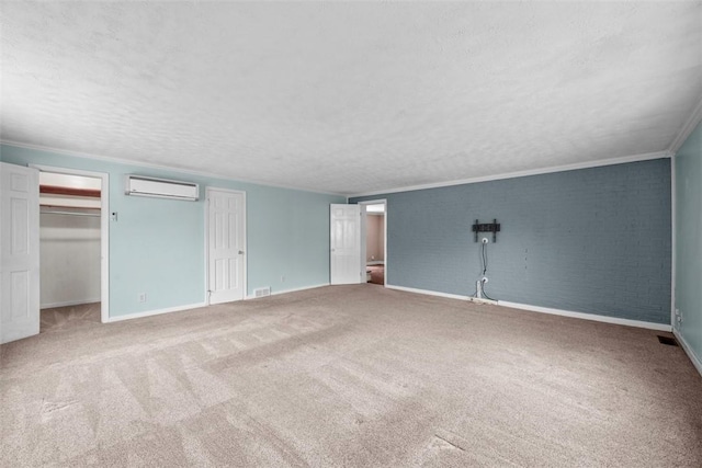 unfurnished bedroom with baseboards, a wall mounted air conditioner, a textured ceiling, and carpet flooring