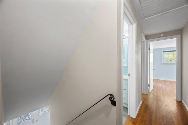 corridor with baseboards, wood-type flooring, and attic access