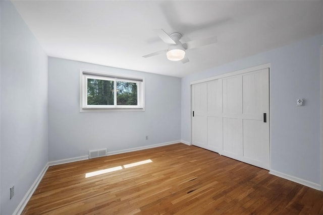 unfurnished bedroom featuring baseboards, visible vents, wood finished floors, and a closet