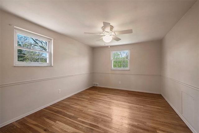 unfurnished room with baseboards, a ceiling fan, wood finished floors, and visible vents