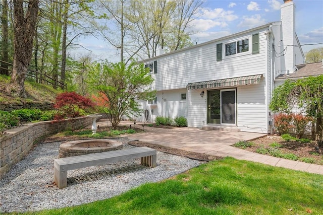 back of house featuring a chimney, a patio area, and an outdoor fire pit