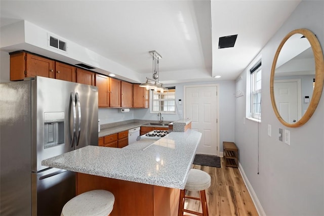 1928 Shamokin, South Side, PA 15203 - kitchen featuring brown cabinetry, visible vents, a sink, a breakfast bar, and white appliances