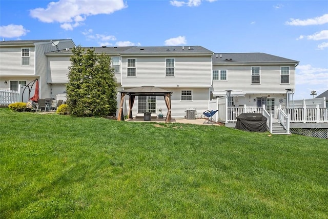 back of house featuring central air condition unit, a deck, a gazebo, and a yard