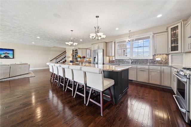 1043 Blackthorne Dr, Penn Twp Wml, PA 15644 - kitchen with a notable chandelier, appliances with stainless steel finishes, a breakfast bar, a center island, and dark wood-style floors