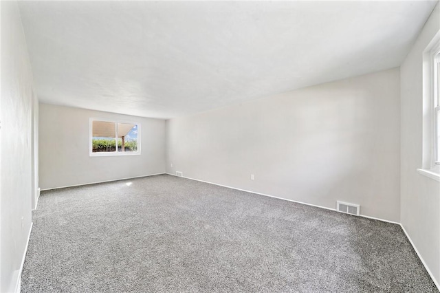empty room with baseboards, visible vents, and carpet