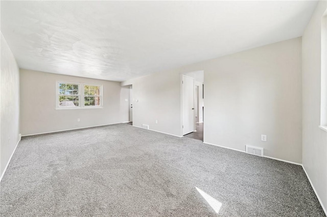 carpeted spare room with visible vents and baseboards