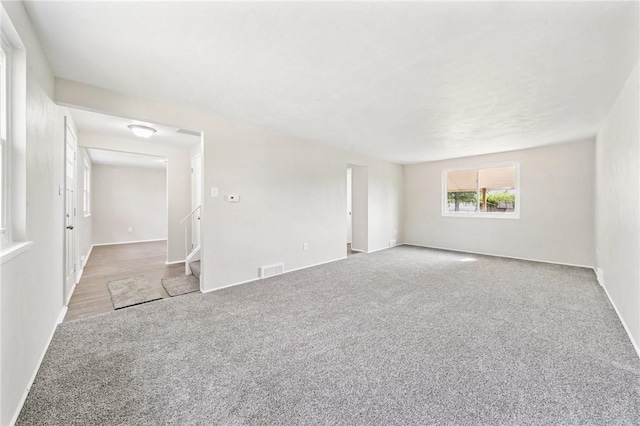 unfurnished room featuring baseboards, carpet, stairs, and visible vents