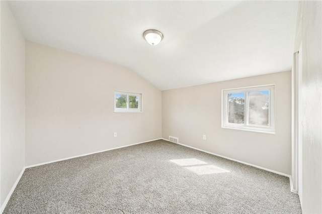 carpeted empty room with baseboards, vaulted ceiling, and visible vents