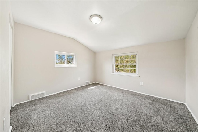 carpeted empty room with visible vents, baseboards, and lofted ceiling