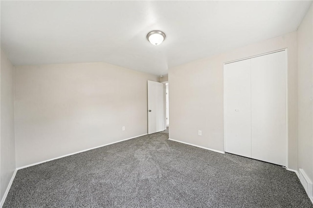 unfurnished bedroom featuring baseboards, lofted ceiling, and carpet
