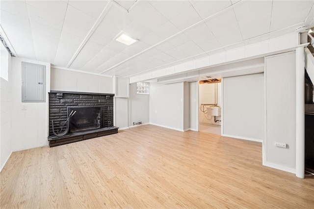 unfurnished living room with a stone fireplace, baseboards, wood finished floors, and electric panel