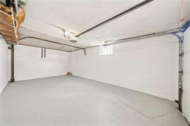 garage featuring concrete block wall and a garage door opener