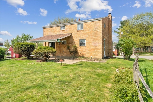 back of property featuring a lawn, a chimney, and brick siding