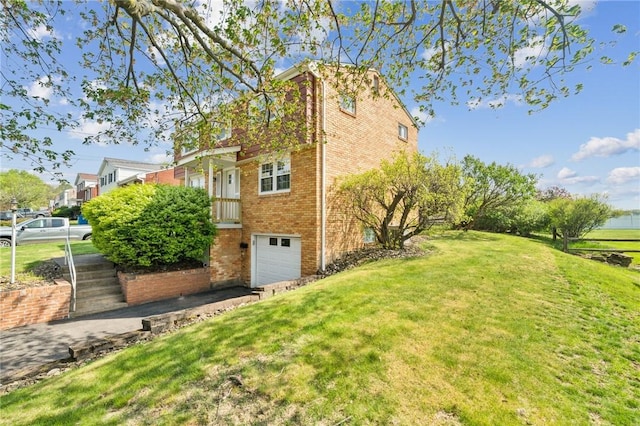 view of property exterior with brick siding, an attached garage, a yard, and driveway