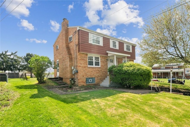 back of house featuring brick siding, a lawn, fence, and a chimney